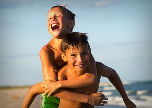 Boy piggyback on another boy at the beach