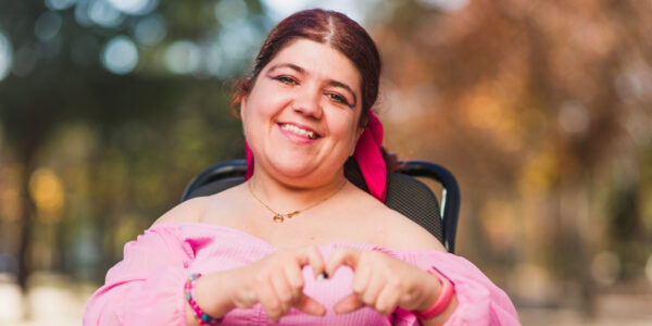 Woman in a wheelchair making a heart with her hands