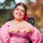 Woman in a wheelchair making a heart with her hands