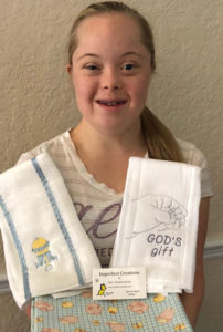 Photo of Faith-Christina holding the baby blankets she's made