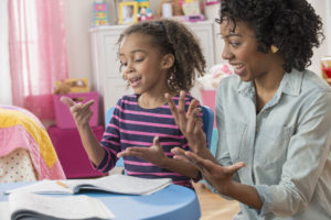 Mother helping daughter do math homework in playroom