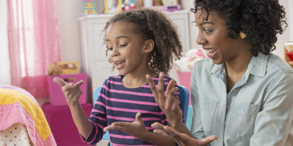 Mother helping daughter do math homework in playroom