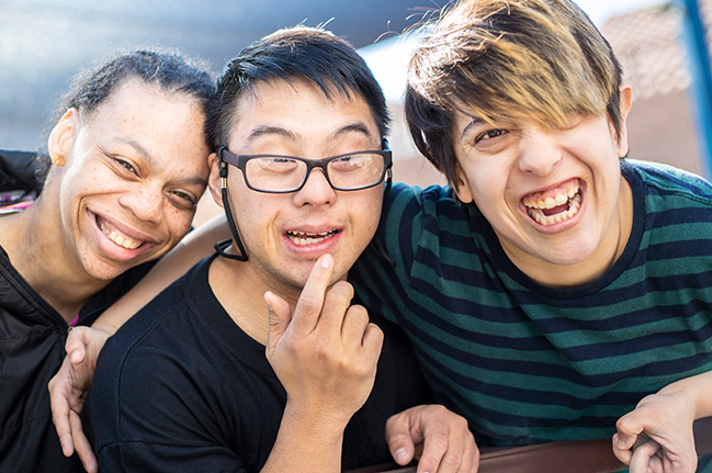 Three diverse friends smiling and laughing at the camera