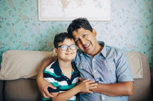 Hispanic father and son smiling on couch