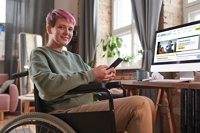 Ambiguously gendered person smiling and holding phone in wheelchair